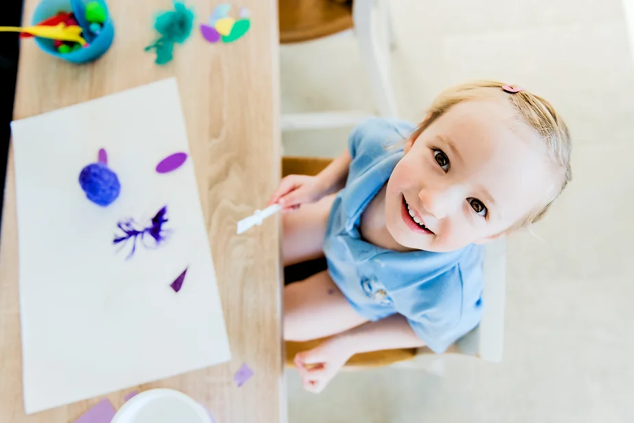 Smiling girl painting, to help calm after school meltdowns.