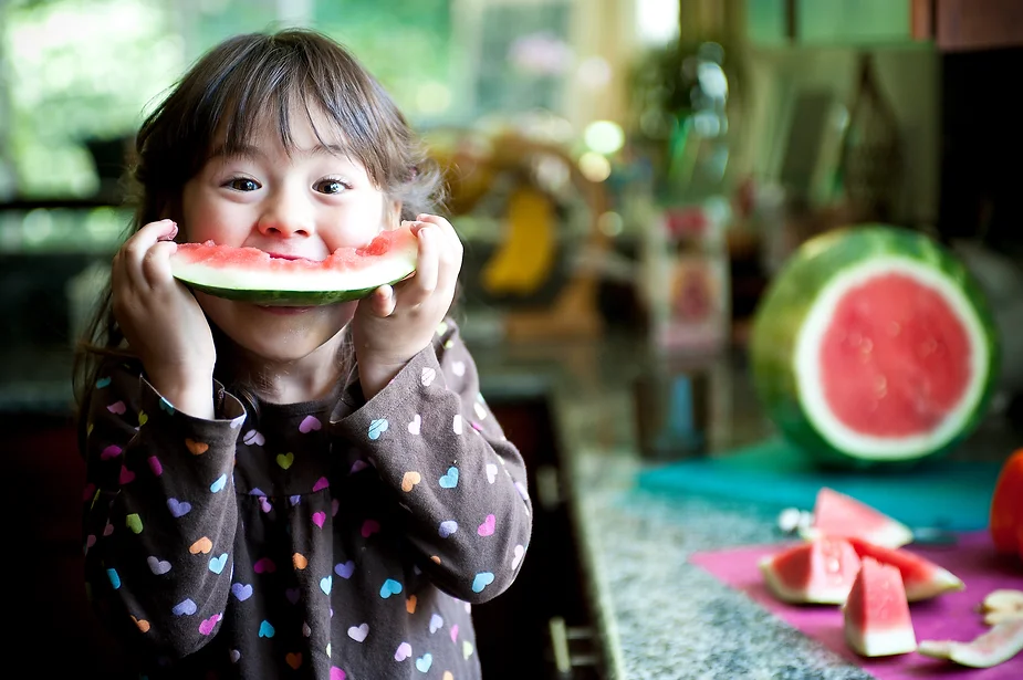 Girl eating watermelon, an after school snack to help calm after school meltdowns.