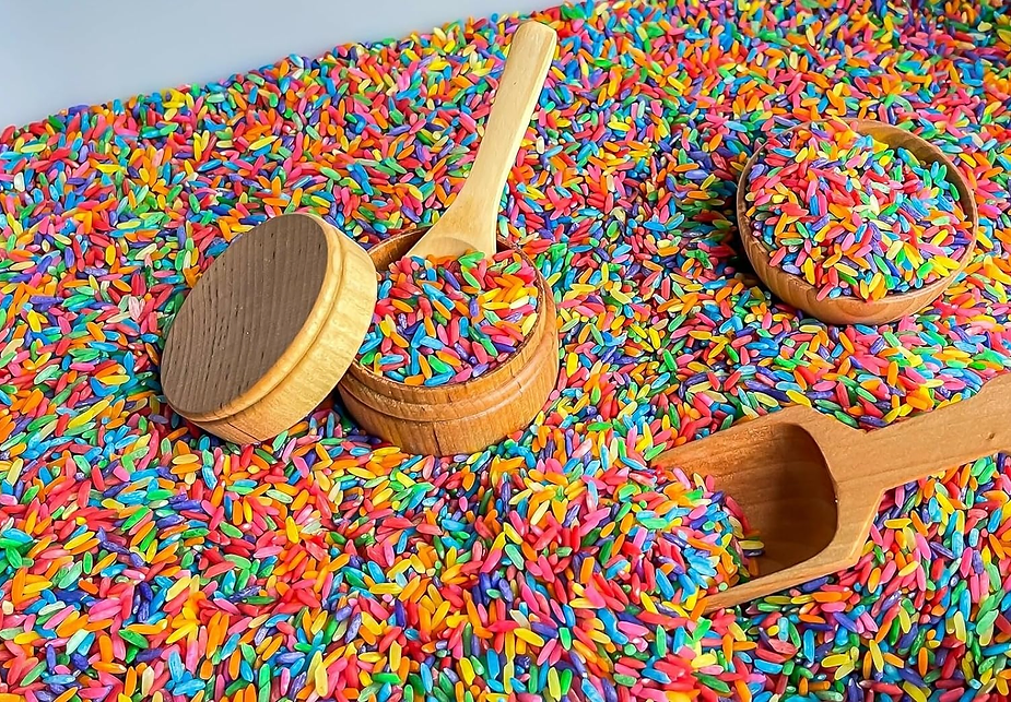 Scooping and pouring colorful rice, a sensory activities for an autistic child.