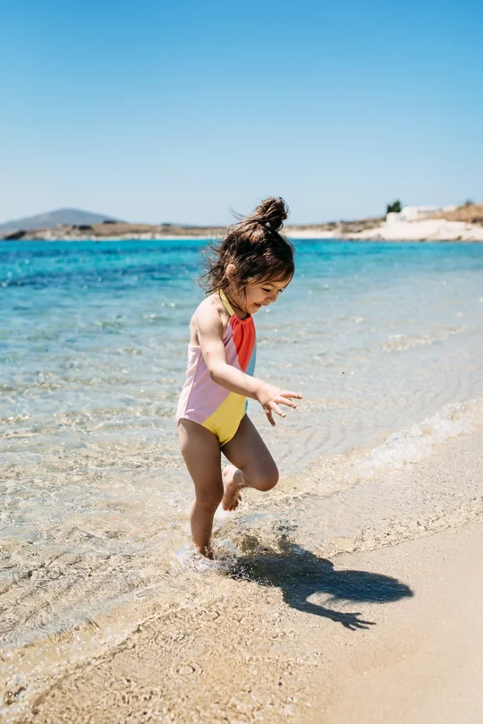 Little girl splashing in water during a family beach day