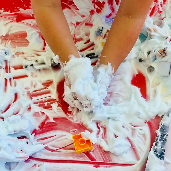 Kid playing with their hands in the Shaving Cream and LEGO Sensory Bin