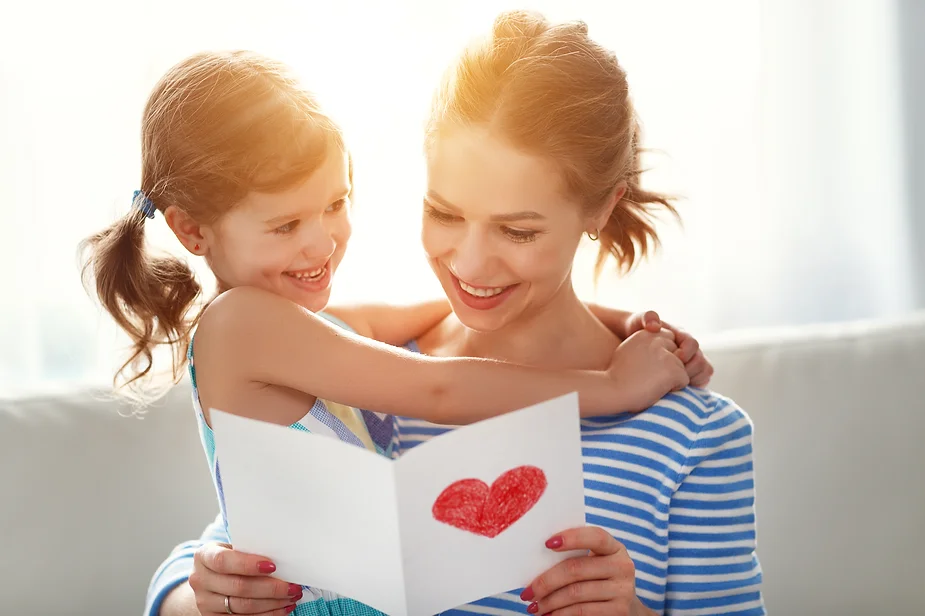 Mother reading card with daughter, a love language for an autistic child.