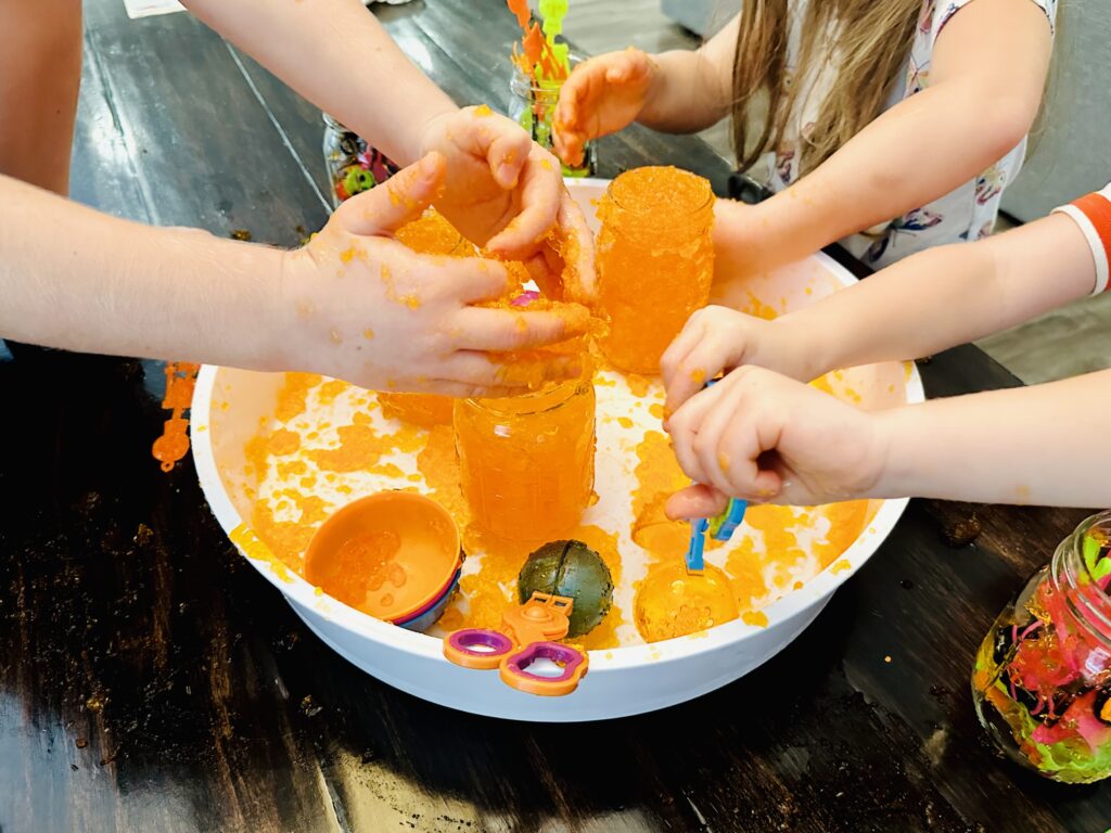 Kids scooping Jello into mason jars.